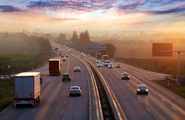 Trucks and cars on a divided highway at sunset