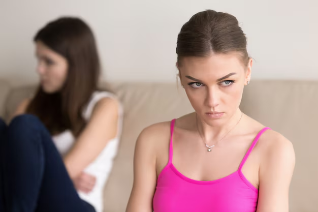 Upset woman on a sofa with another woman sitting turned away behind her