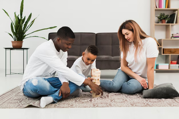 Parents playing a wooden block stacking game with their son on the floor
