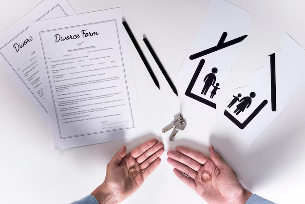 Hands beside divorce forms, house keys and a torn paper family cut-out
