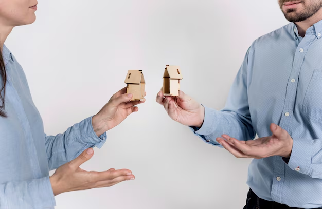 Man and woman each holding half of a small wooden house model