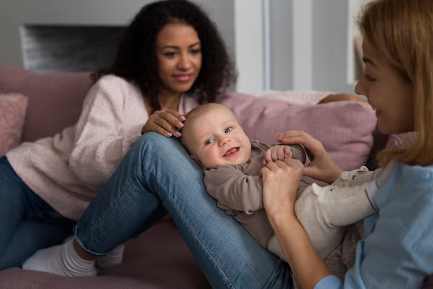 Two women on a sofa playing with a smiling baby
