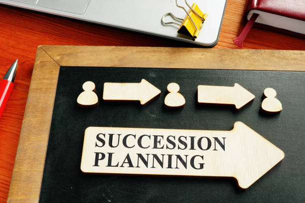 Wooden figures and arrows on a chalkboard with a Succession Planning sign