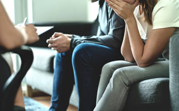 Woman covering her face with her hands during a counseling session, a man beside her