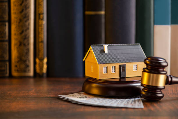 Model house and gavel resting on cash in front of law books
