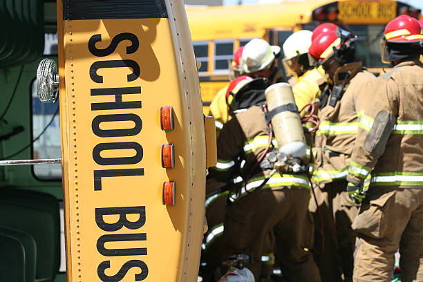 Firefighters in turnout gear gathered beside a yellow school bus