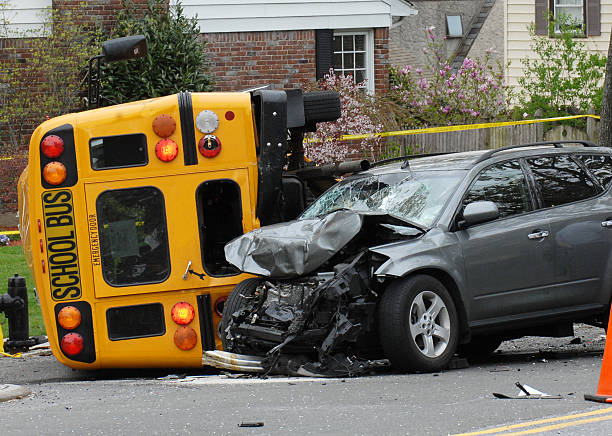 Overturned yellow school bus and a wrecked grey SUV on a residential street