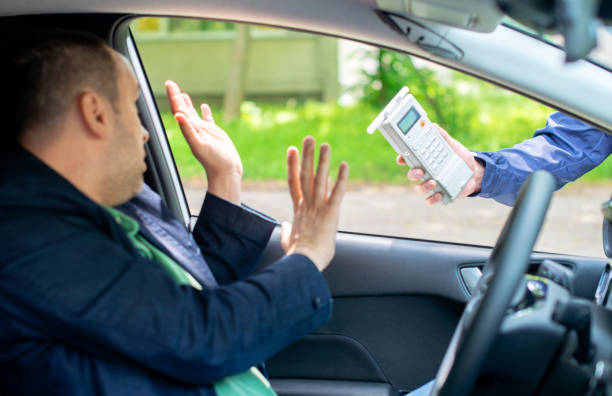 Driver holding up his hands to refuse a breathalyzer offered through the car window