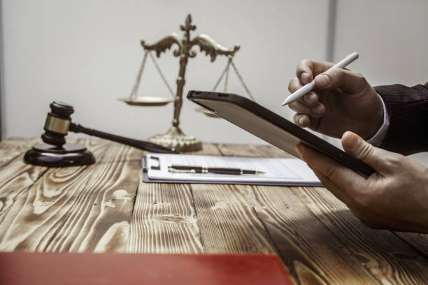 Hands writing on a tablet beside a gavel and scales of justice
