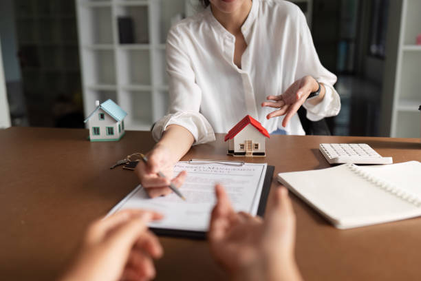 Adviser presenting a property document across a desk with two model houses