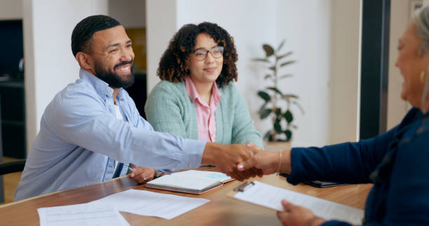 Young couple shaking hands with an advisor across a desk