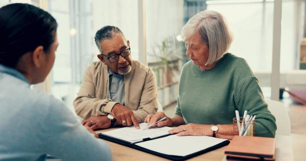 Older couple reviewing and signing a document with an advisor at a desk
