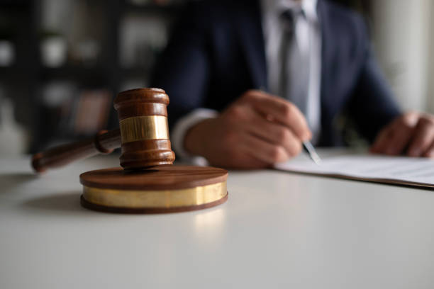 Wooden gavel on a desk with a lawyer signing papers in the background