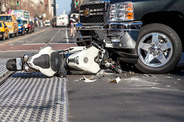 White motorcycle lying on a city street after a collision with a pickup truck