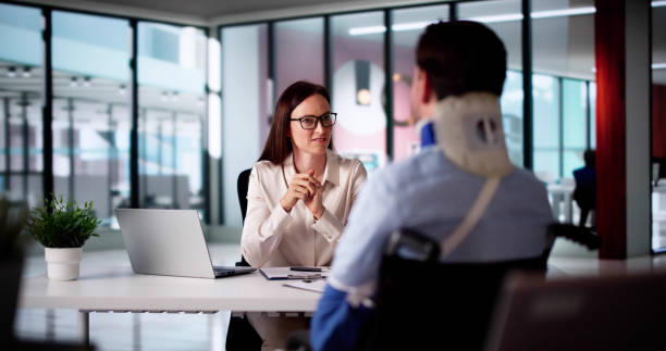 Woman at an office desk meeting with a man wearing a neck brace