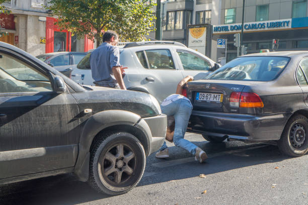 Two drivers inspecting damage after a rear-end collision on a city street
