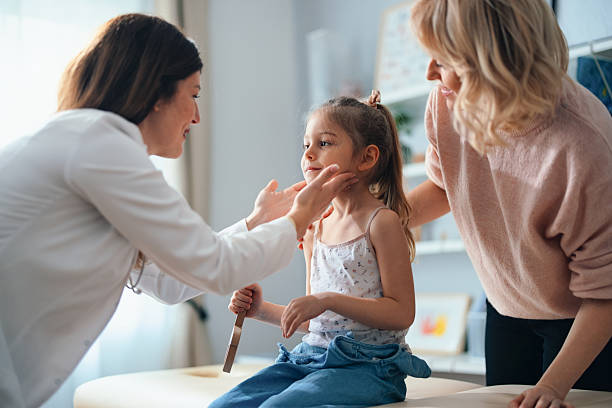 Doctor examining a young girl while her mother looks on