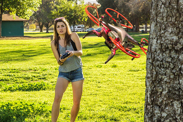Woman flying a red quadcopter drone with a remote controller in a park